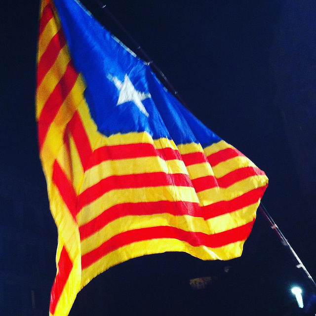 En röd- och gulrandig flagga. På ena sidan är det en blå triangel med en vit stjärna på.