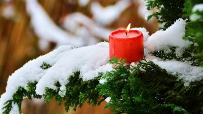 Ett rött ljus brinner i en gran med snö