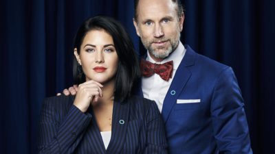 Peter Jihde har blå kavaj och röd slips. Han har lagt sin hand på Mollys axel. Molly har en blårandig kostym och håller ena handen lyft till hakan.