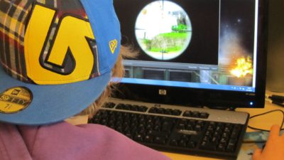 Bild på en person bakifrån som sitter och spelar datorspel.