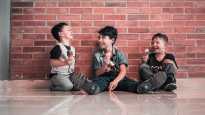 Tre pojkar äter glass och skrattar