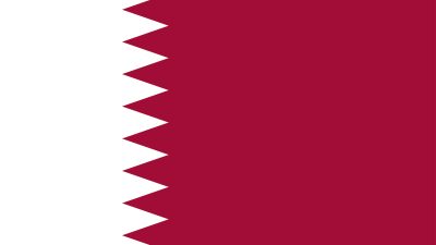 Landet Qatars flagga. Den är vit och vinröd. Färgerna möts i ett sicksack-mönster.